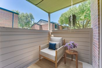 A wooden chair with a cushion and a small table with flowers on it.